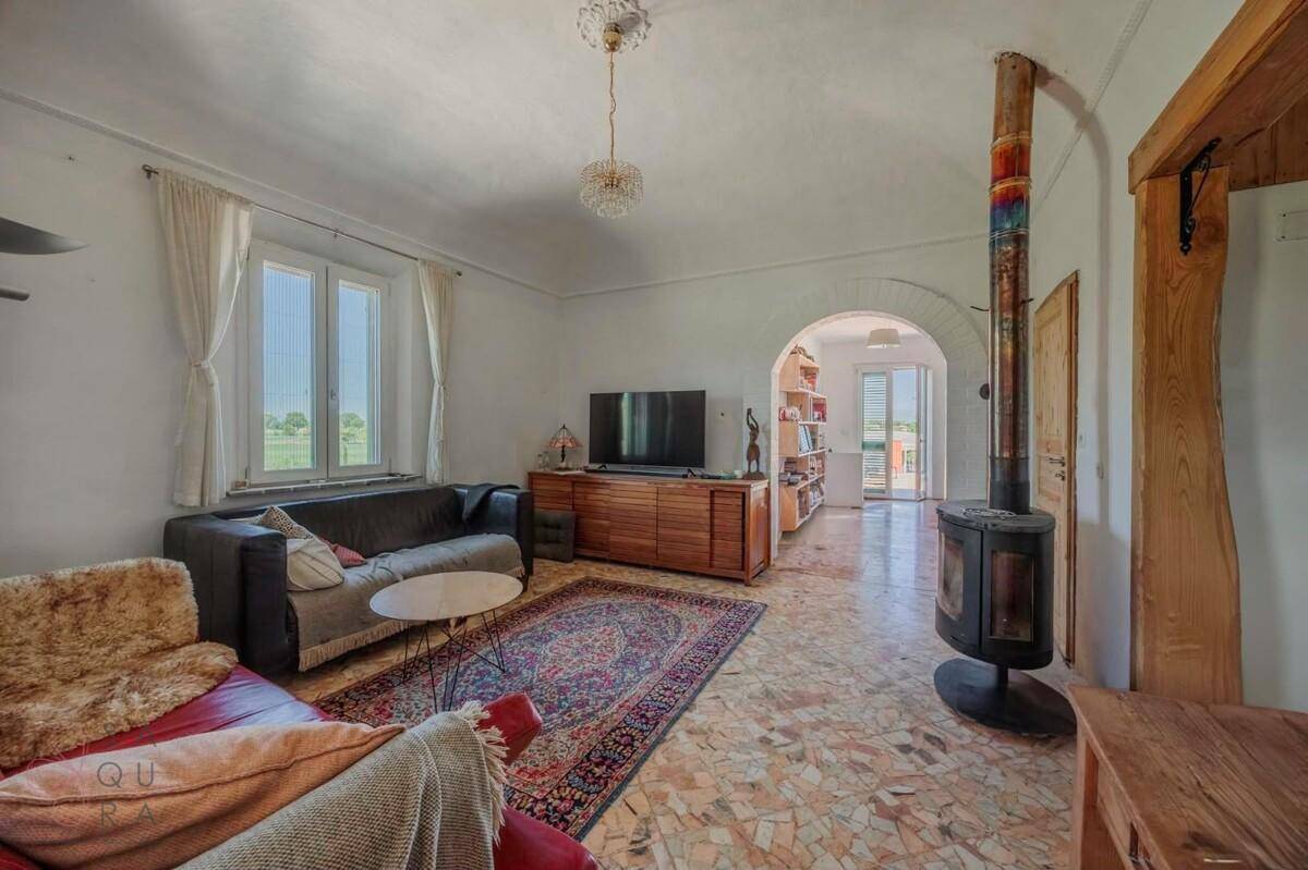 Geräumiges Wohnzimmer mit Terrazzoboden, Holzofen und Blick in die Ferne.