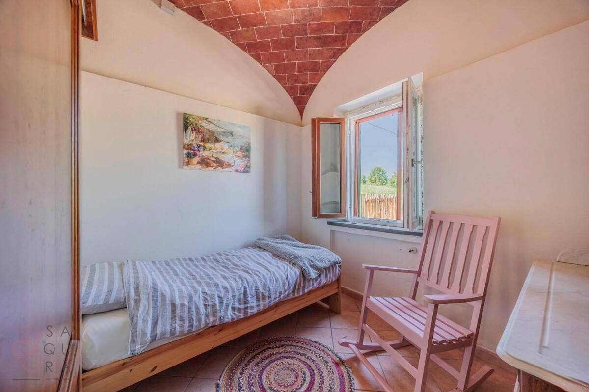 Kleines Schlafzimmer mit Einzelbett, Gewölbedecke aus Ziegeln und Fenster.