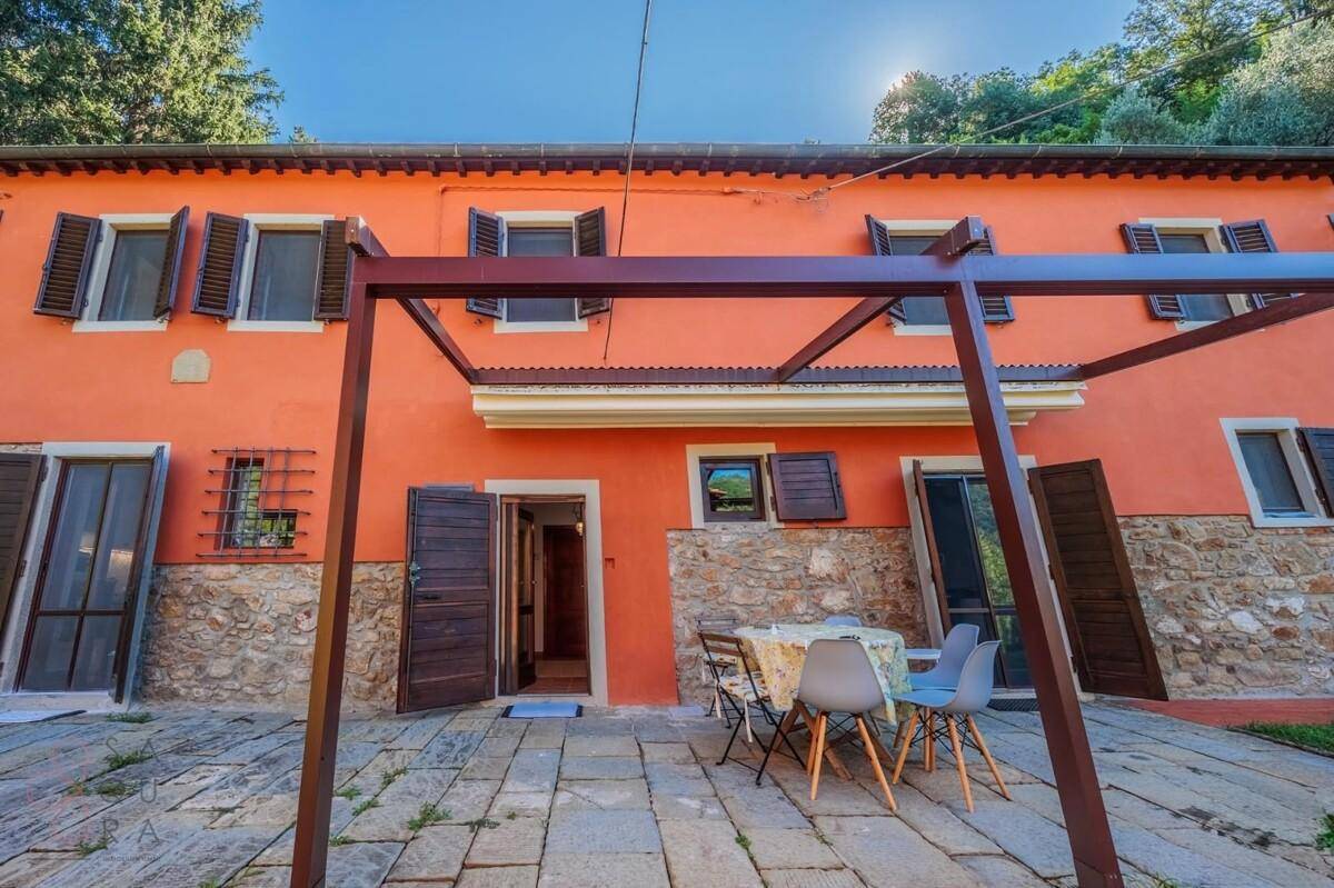 Gemütliche Steinterrasse mit Esstisch und Stühlen vor der traditionellen Hausfassade.
