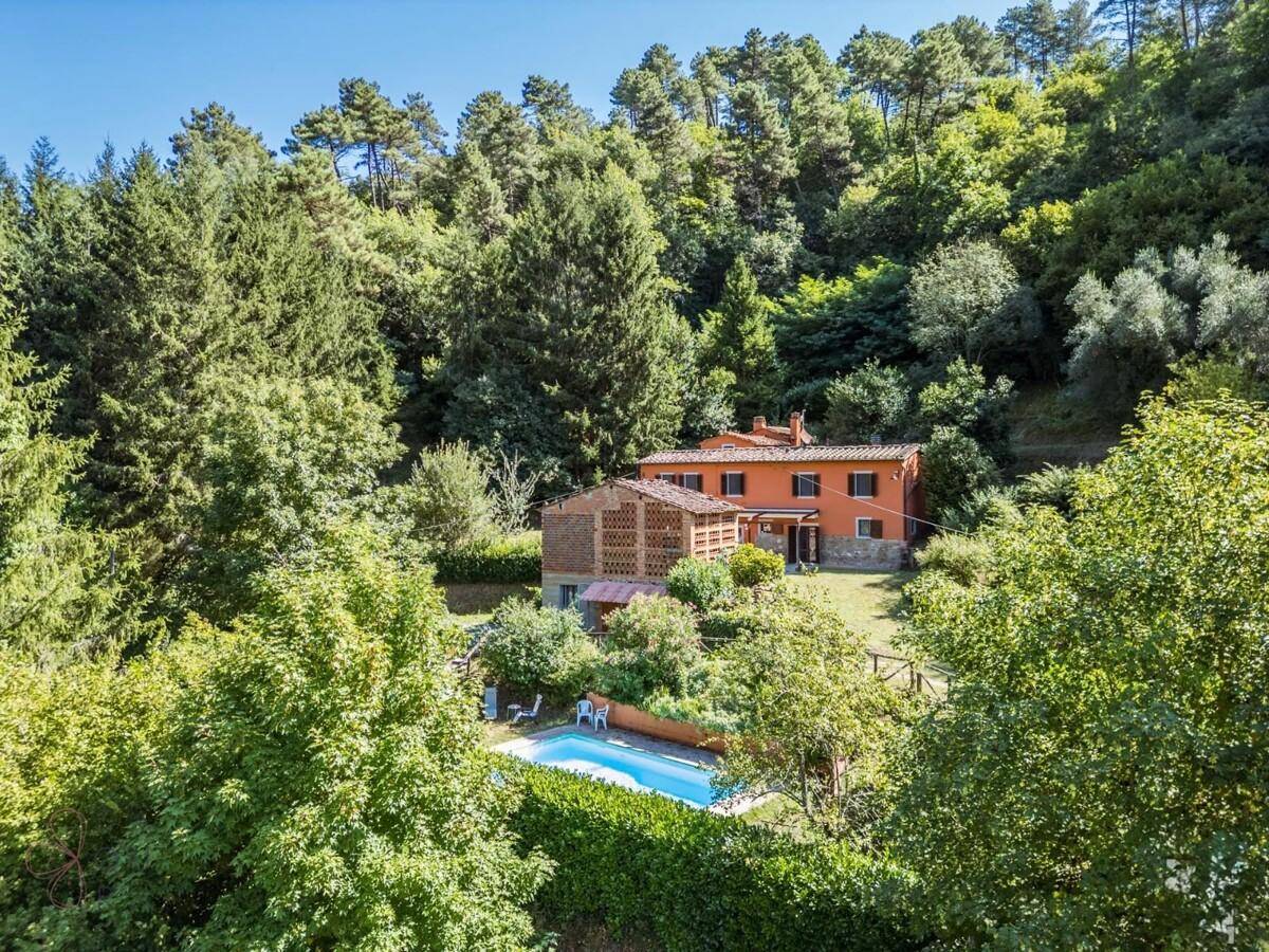 Anwesen mit traditionellem Landhaus und einem erfrischenden Pool, eingebettet in eine grüne Hügellandschaft.