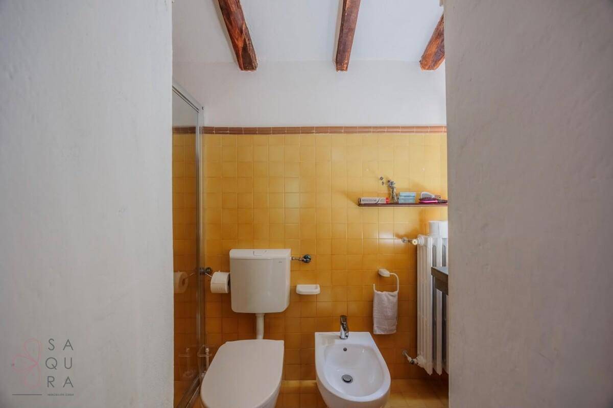Kleines WC mit gelben Fliesen, Toilette und Bidet, funktional und hell.
