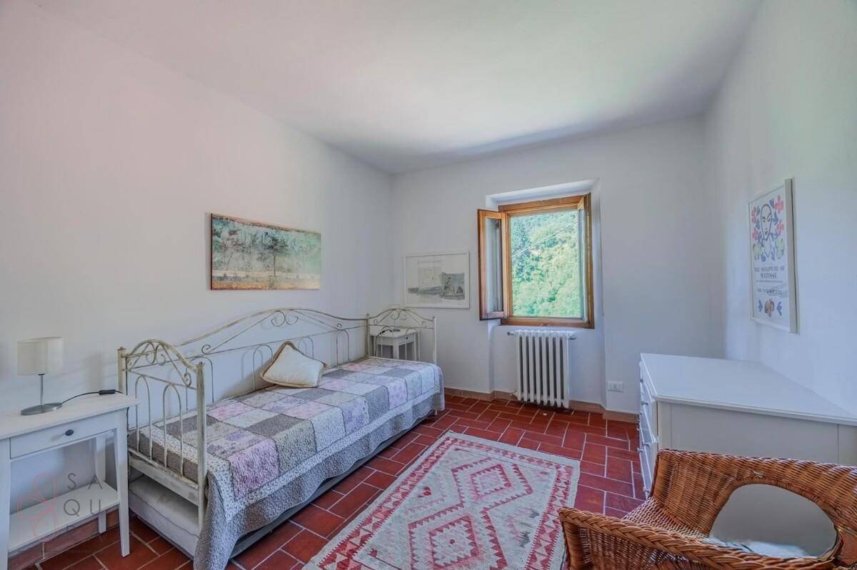 Freundliches Schlafzimmer mit Terrakottaboden, Tagesbett und Blick auf die umliegende Natur.