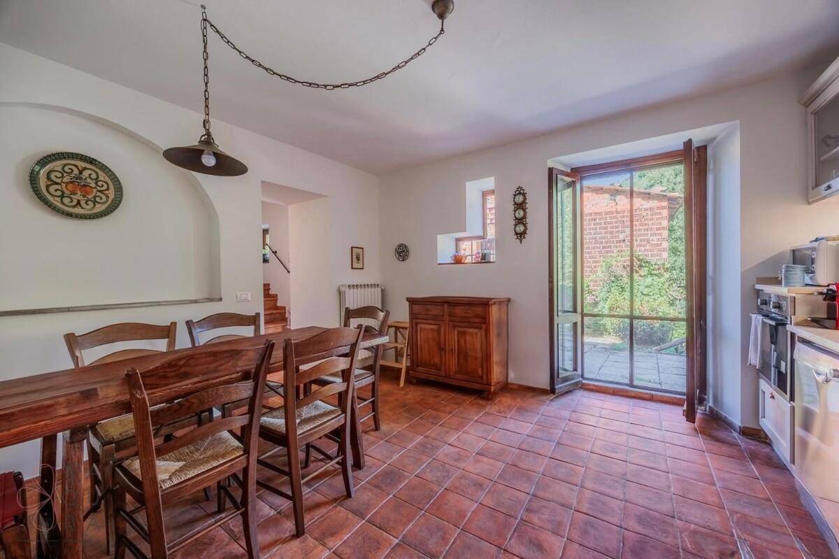 Geräumige Wohnküche mit Holztisch, Terrakottaboden und Zugang zum Außenbereich.