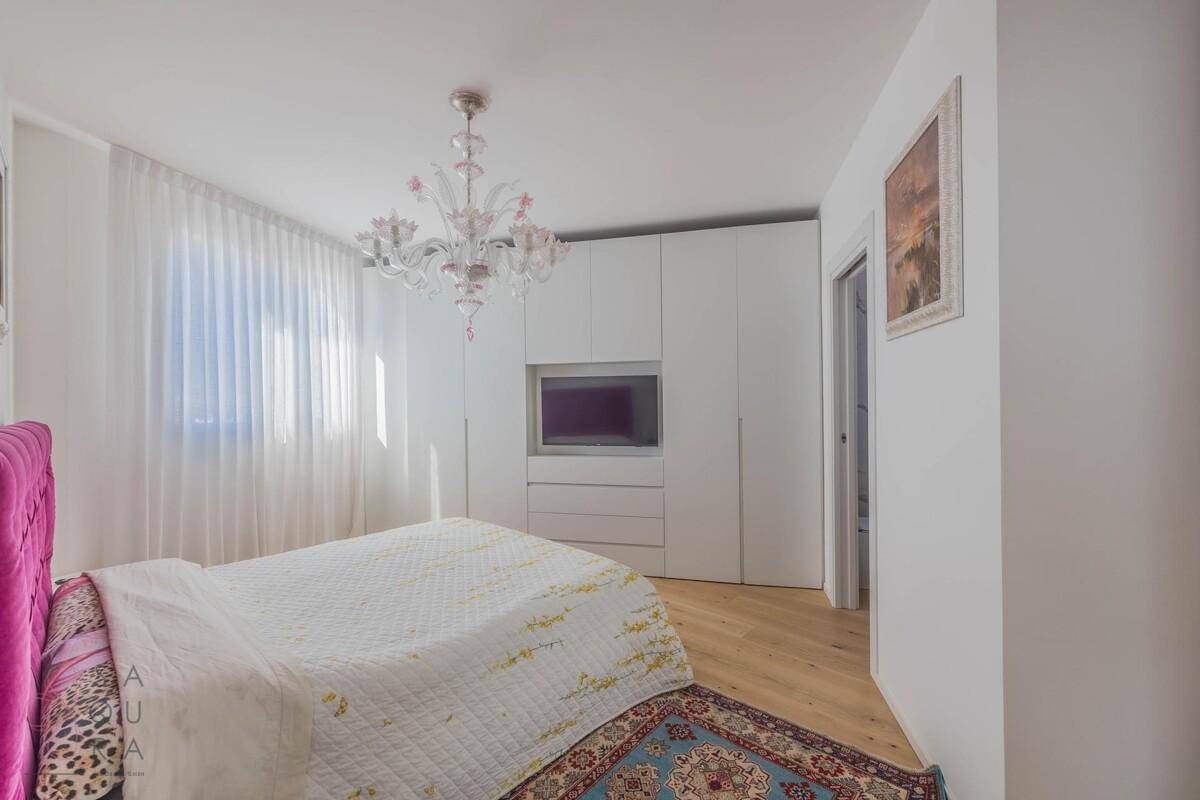 Schlafzimmer mit Holzboden, Einbauschränken und einem auffälligen Kronleuchter.