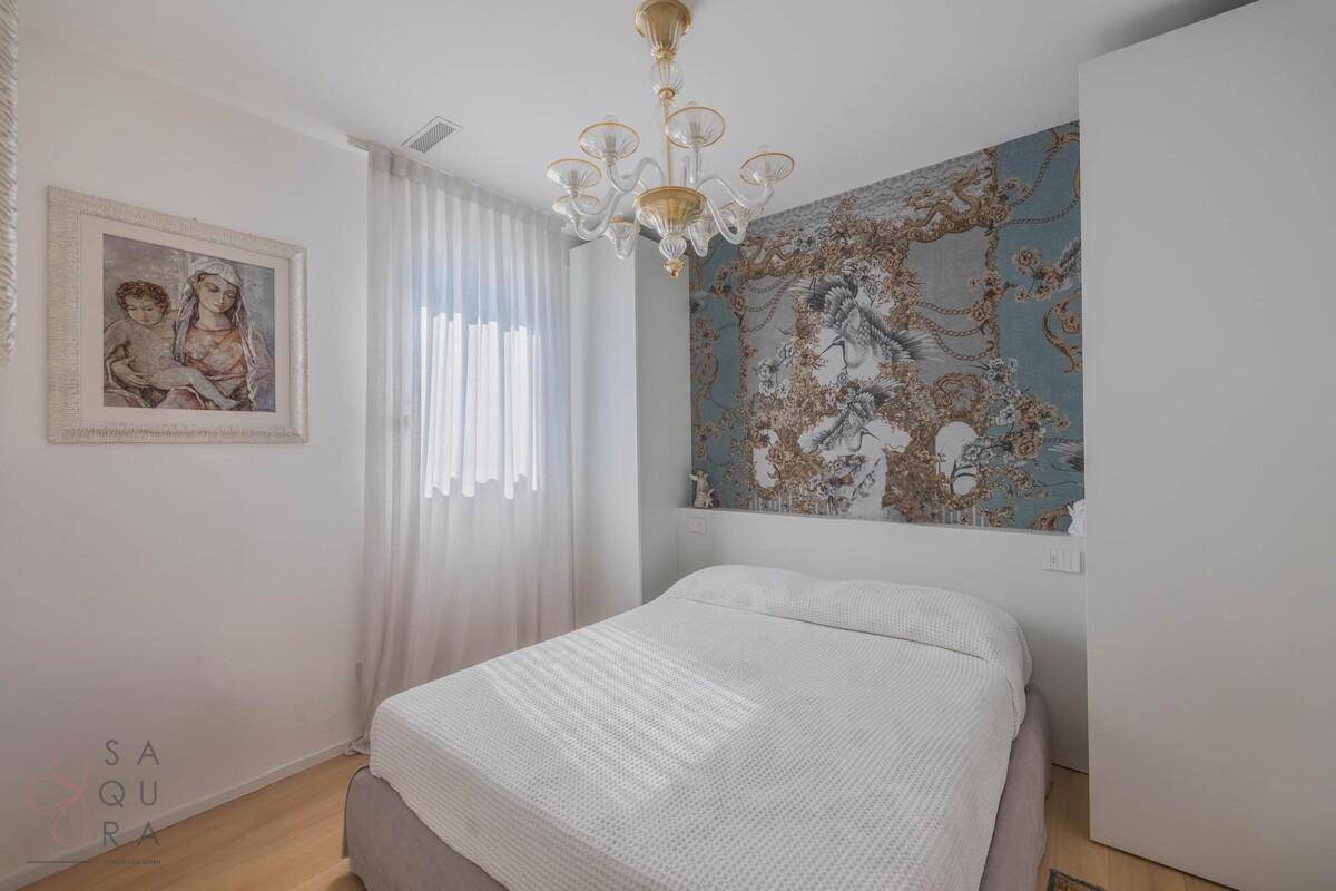 Schlafzimmer mit Holzboden, dekorativer Tapete und elegantem Kronleuchter.