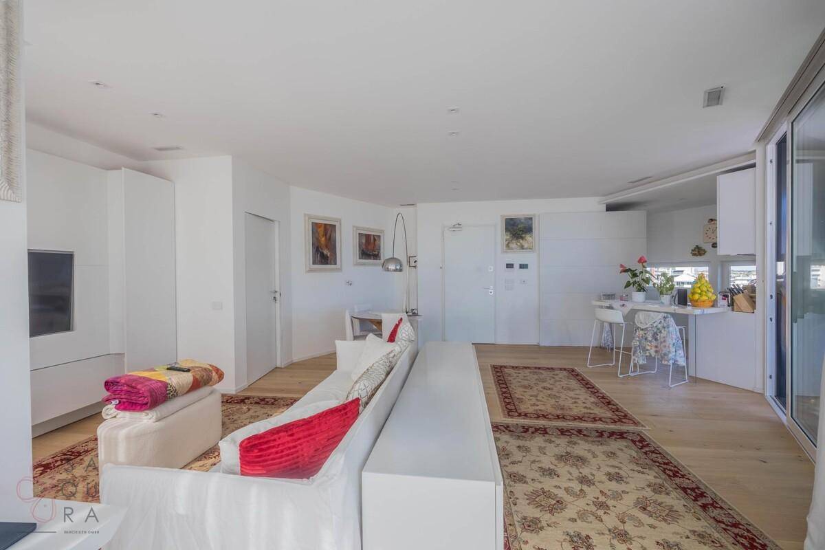 Offener Wohnbereich mit bequemen Sofas, Holzboden und Blick auf den Essbereich und die Küche.