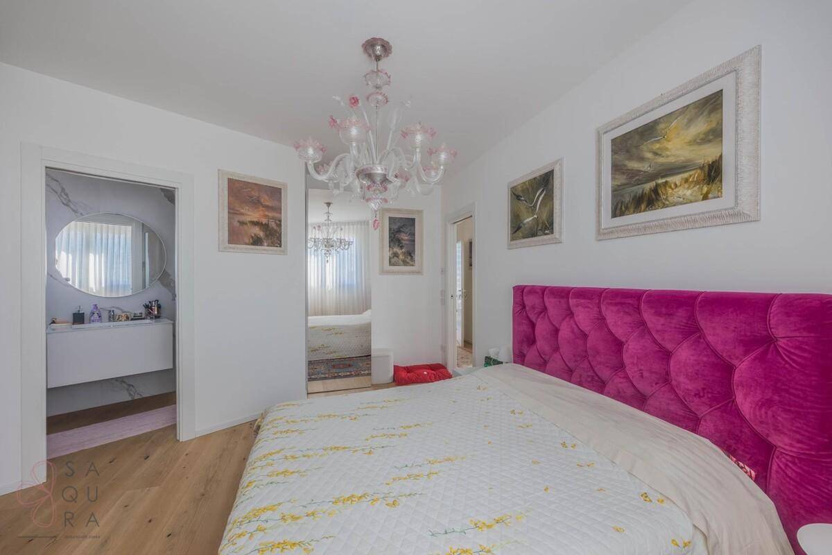 Schlafzimmer mit Holzboden, pinkem Bett und Zugang zu einem modernen Badezimmer.