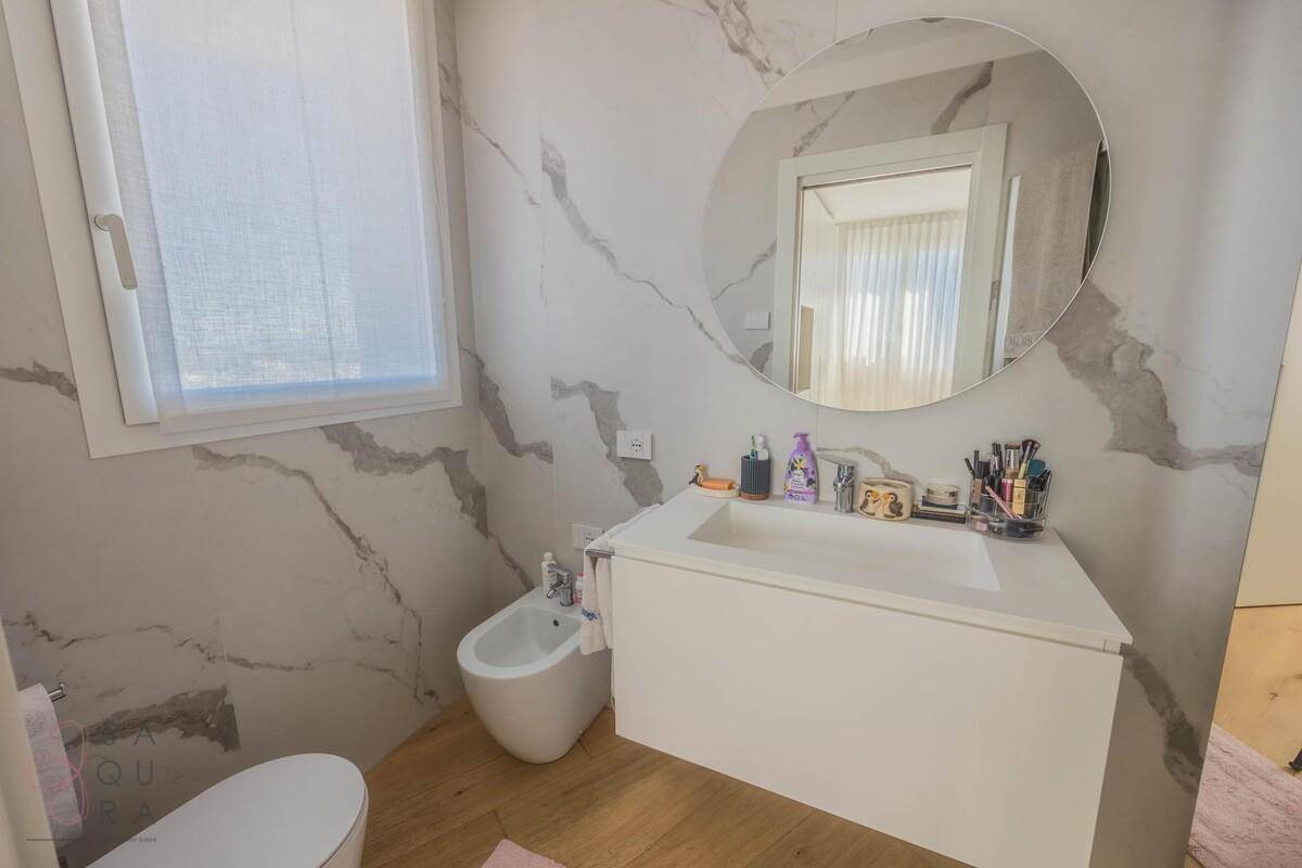 Elegantes Badezimmer mit Marmoroptik-Wänden, Bidet und Einzelwaschbecken.