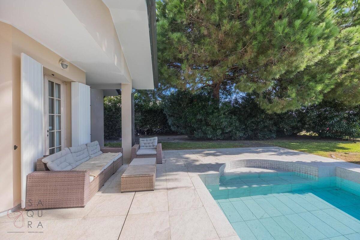 Gemütliche Terrasse mit Rattanmöbeln direkt am Pool, ideal für Entspannung im Freien.