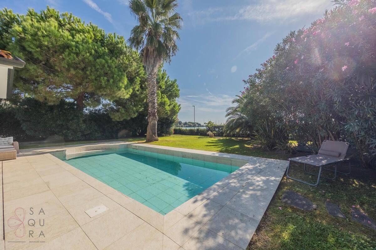 Entspannender Poolbereich im Garten mit Liegestuhl und weitem Blick auf das Wasser in der Ferne.
