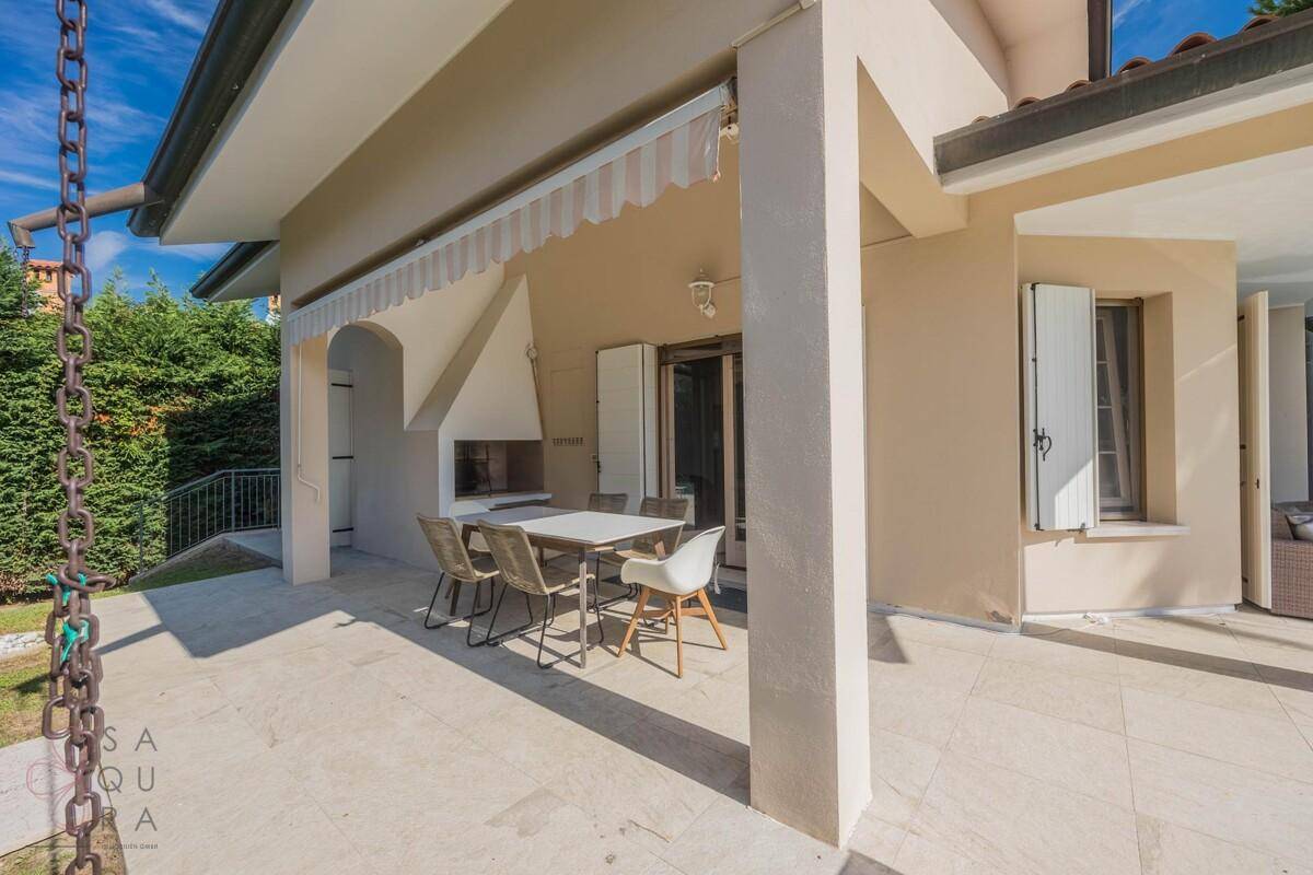 Überdachte Terrasse mit Esstisch und Stühlen, inklusive eingebautem Grillbereich für Mahlzeiten im Freien.