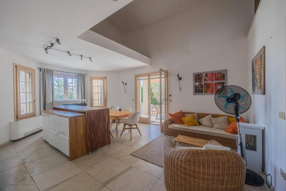 Heller offener Wohn-Essbereich mit integrierter Küche, Fliesenboden und Zugang zur Terrasse.