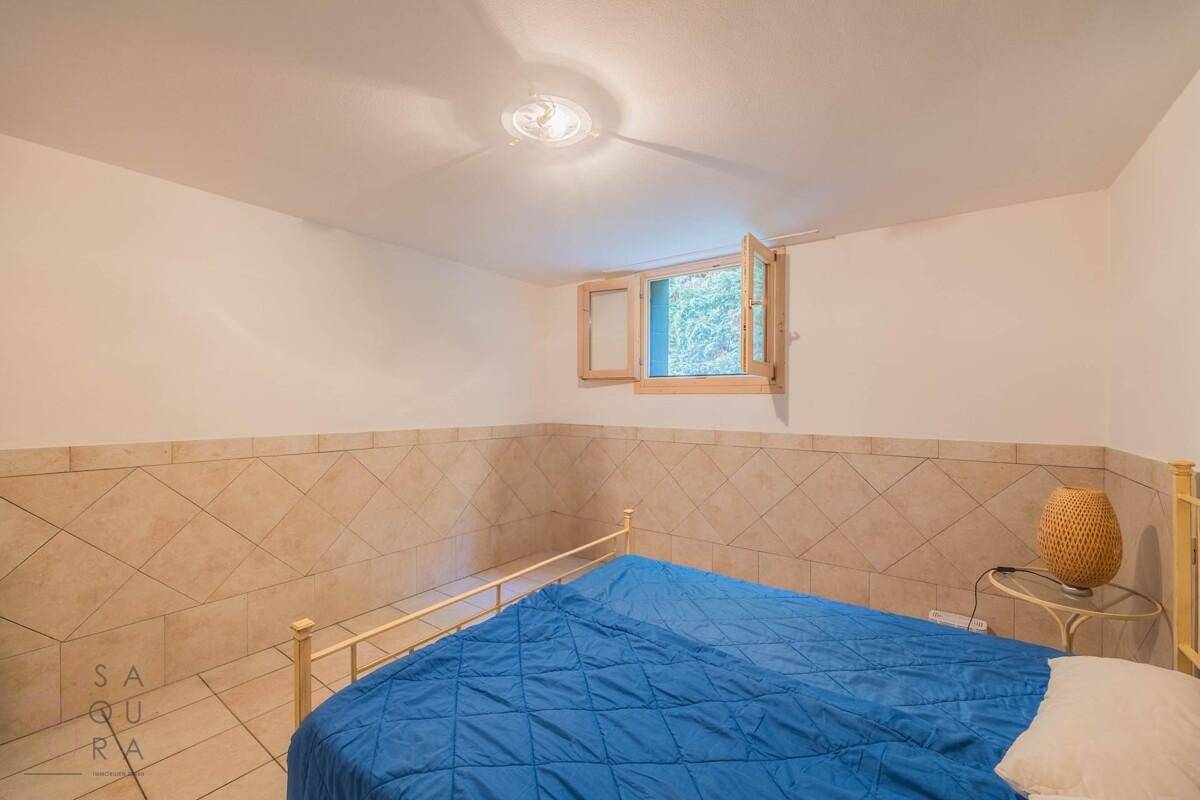 Gemütliches Schlafzimmer im Keller mit Fliesenboden, einem Doppelbett und einem kleinen Fenster.