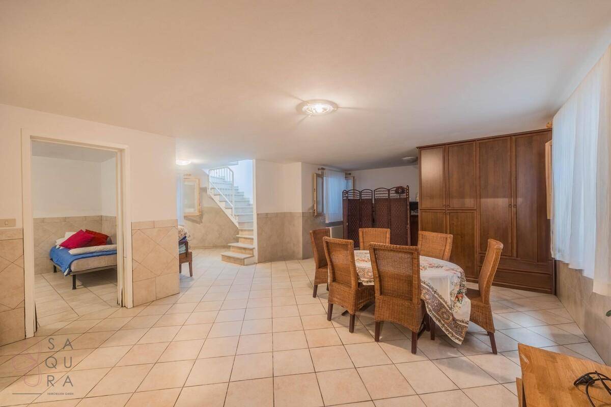 Großer Kellerraum mit Essbereich, Treppenzugang und Fliesenboden, bietet zusätzlichen Wohnraum.
