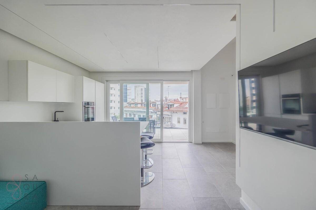 Offener Wohnbereich mit Blick auf die Stadt, großen Schiebetüren und moderner Küche.