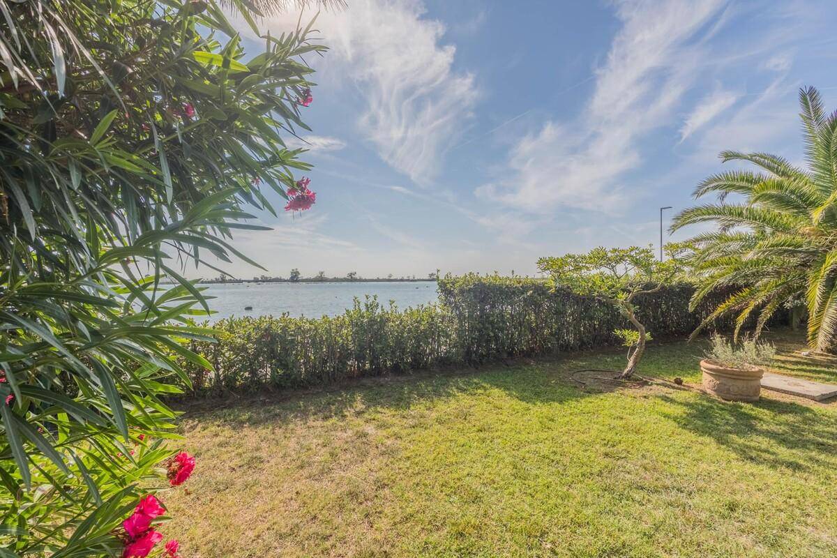 Idyllischer Gartenbereich mit üppiger Vegetation und einem malerischen Blick auf den See.