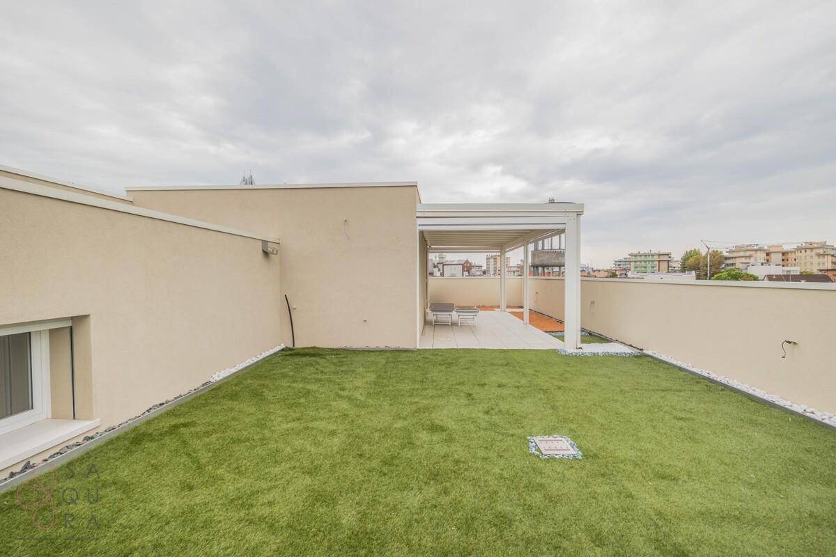 Weitläufige Dachterrasse mit Kunstrasen, Pergola und Platz für Entspannung im Freien.