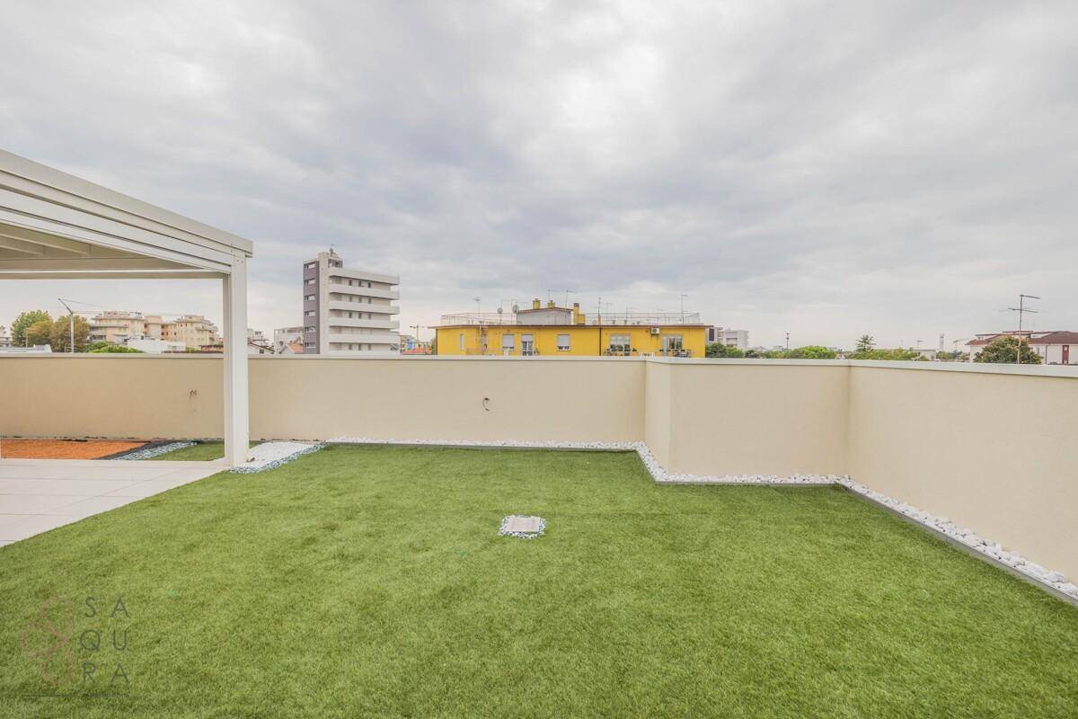 Dachterrasse mit Kunstrasenfläche, Zierkies und weitem Blick über die Stadt.