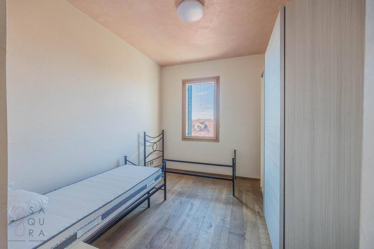 Gemütliches Schlafzimmer mit Holzboden, Einzelbett und einem Fenster, das den Raum erhellt.