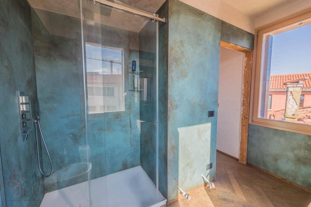 Geräumige begehbare Dusche in einem modernen Badezimmer mit auffälligen blauen Wänden und Fenster.