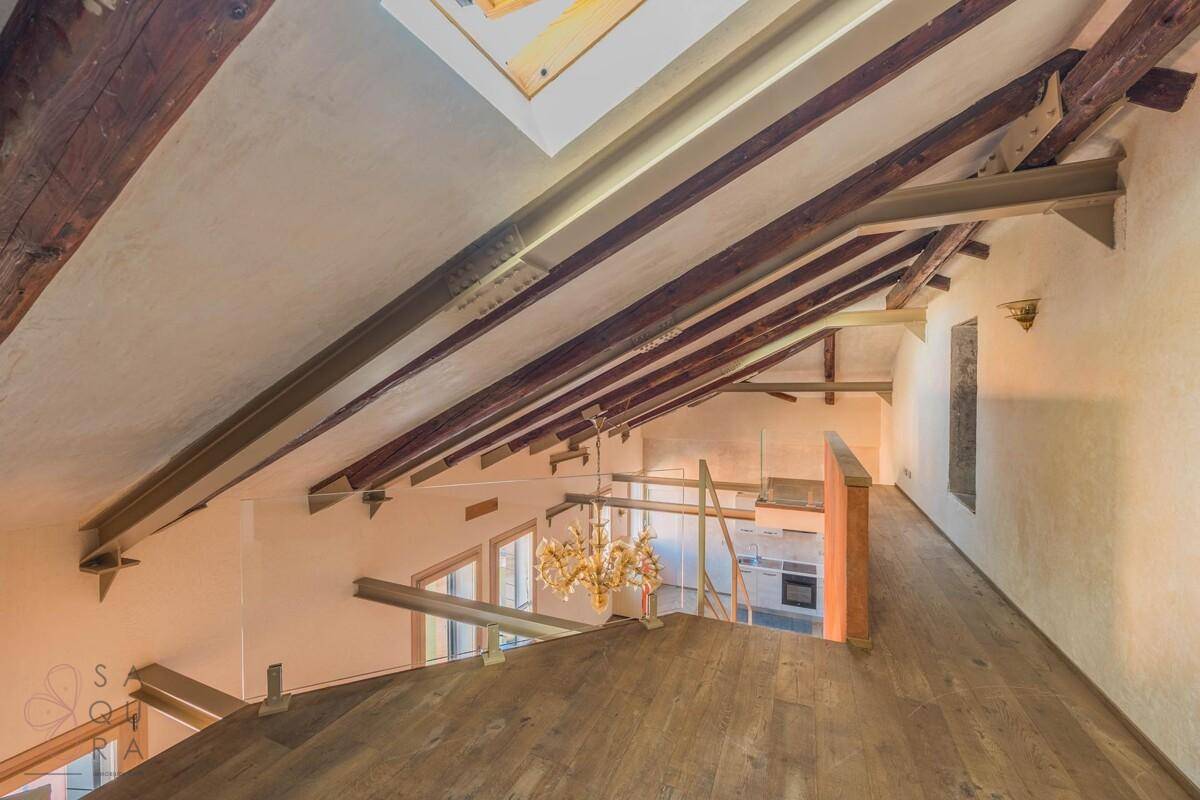 Dachgeschoss mit freiliegenden Holzbalken, Dachfenster und einem weiten Blick über den unteren Wohnbereich.