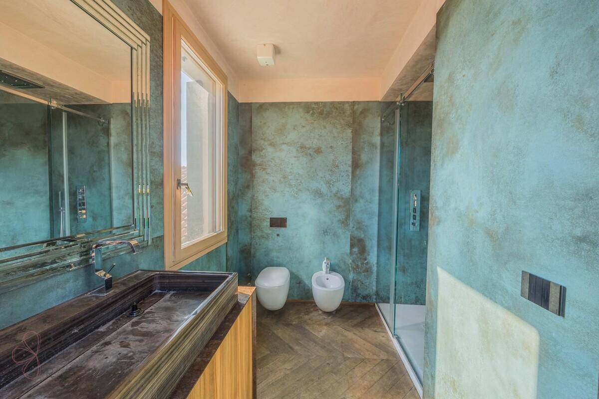 Modernes Badezimmer mit blauen Wänden, großem Waschbecken, wandhängendem WC, Bidet und begehbarer Dusche.