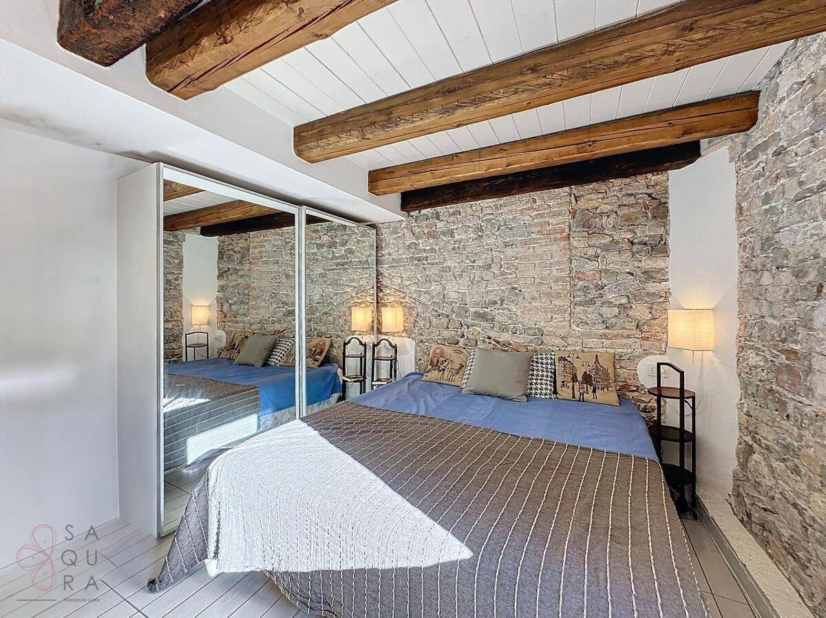 Helles Schlafzimmer mit Ziegelwand, Holzbalken und großem Spiegelschrank.