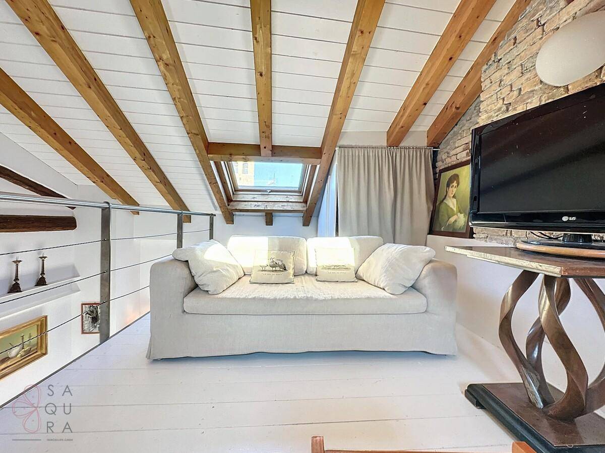 Heller Dachboden-Wohnbereich mit bequemer Couch und Dachfenster für viel Licht.