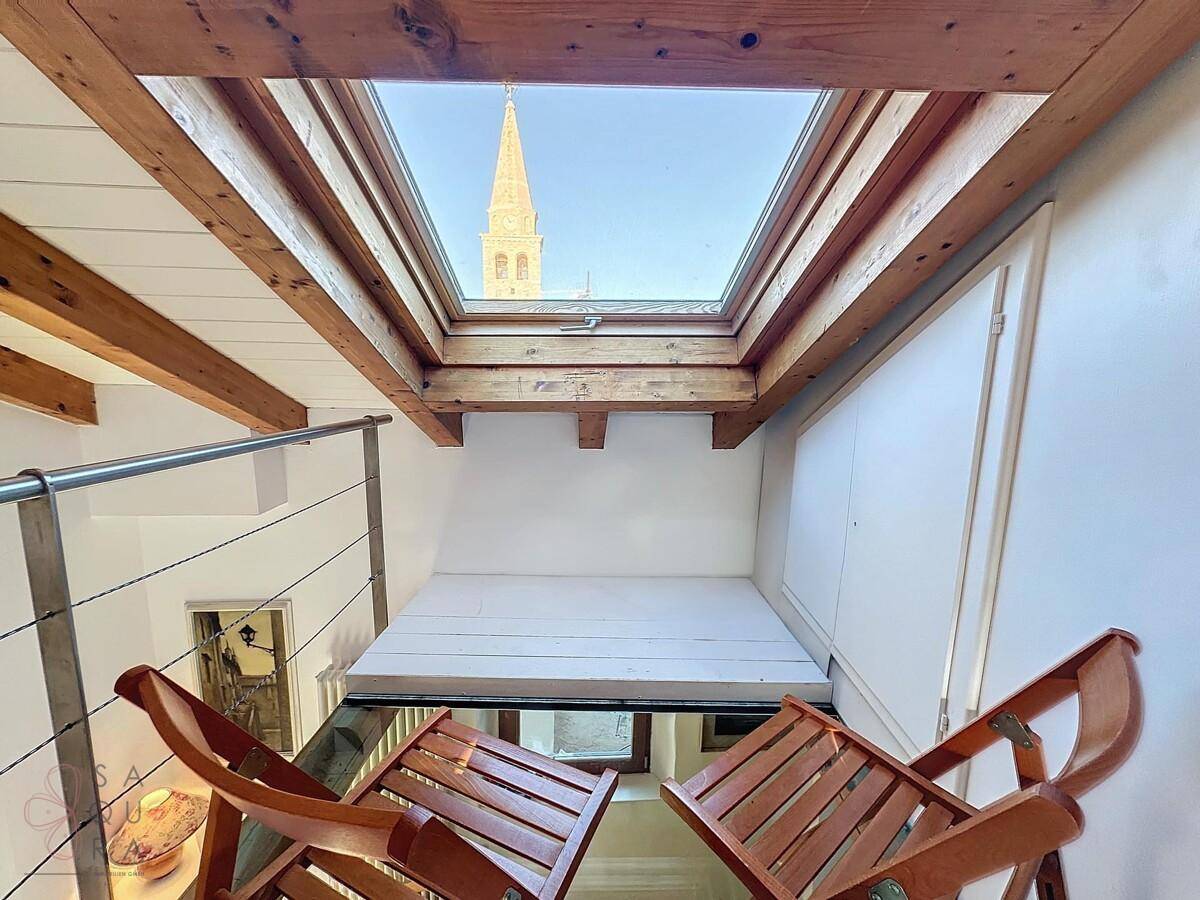 Blick vom Dachboden durch das Dachfenster auf einen Kirchturm und die Dächer der Stadt.