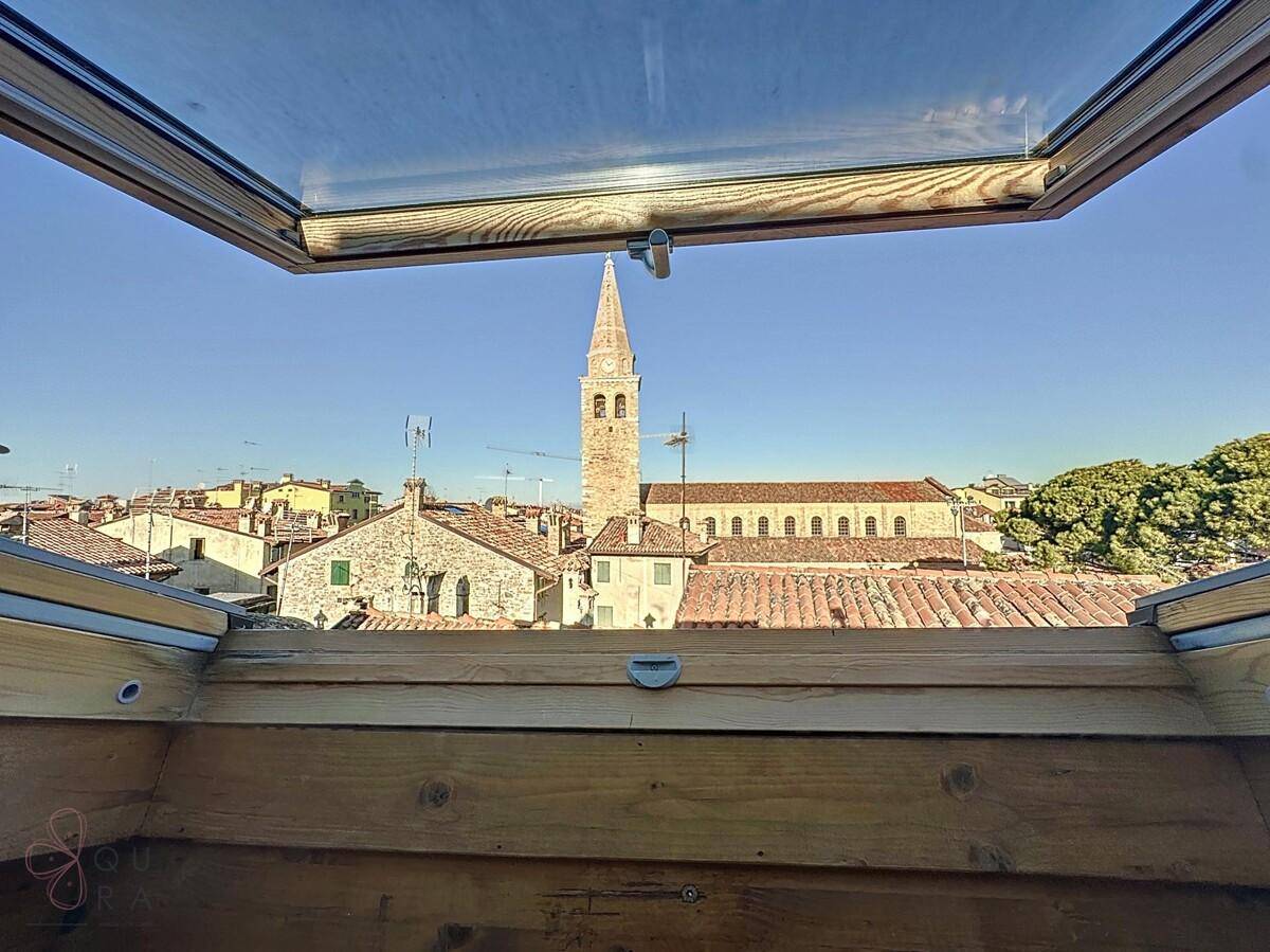 Klarer Blick durch das Dachfenster auf einen historischen Kirchturm und die umliegenden Dächer.
