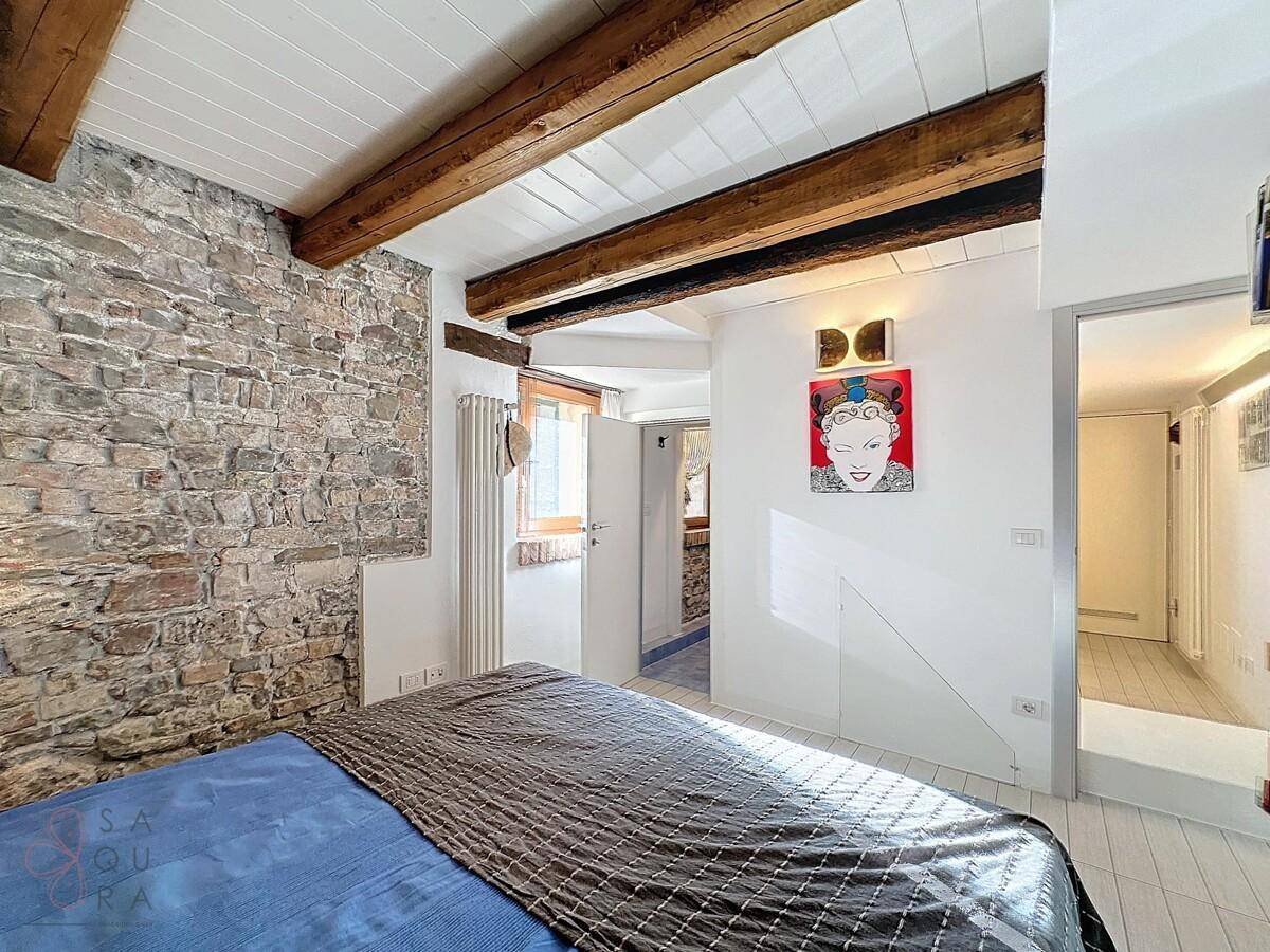 Schlafzimmer mit Ziegelwand und Zugang zu einem angrenzenden Flur.