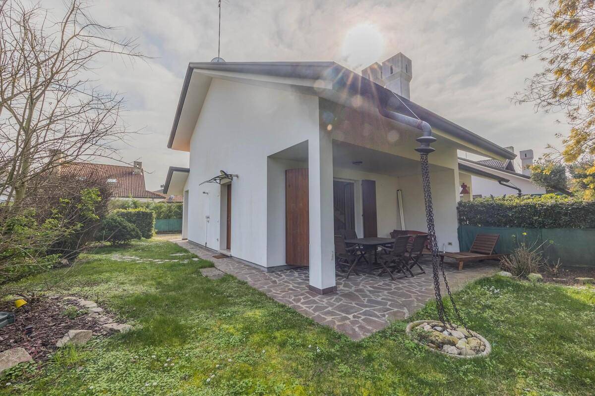 Rückseite des Hauses mit überdachter Terrasse, Gartenmöbeln und Rasenfläche.