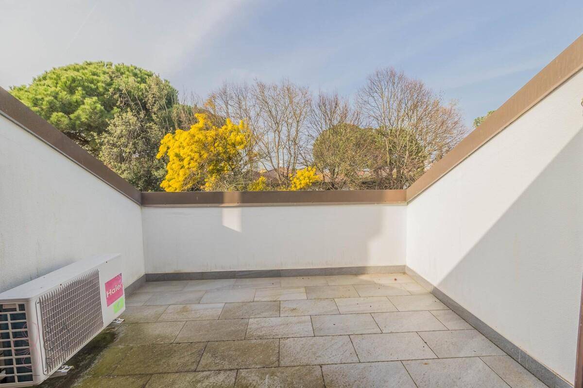Dachterrasse mit Fliesenboden und Blick auf die umliegende grüne Landschaft.