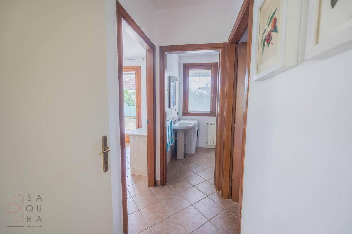 Flur mit Fliesenboden, der zu einem Badezimmer mit Fenster führt.