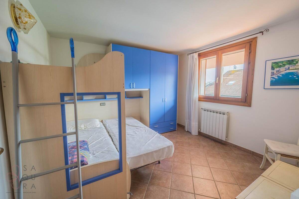 Kinderzimmer mit Etagenbett, blauem Kleiderschrank und Fenster.
