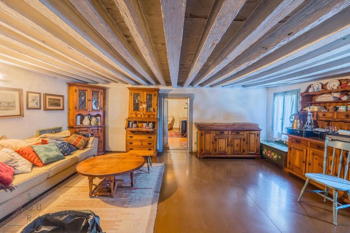 Gemütliches Wohnzimmer mit Holzbalkendecke, traditionellen Möbeln und weichem Teppich.