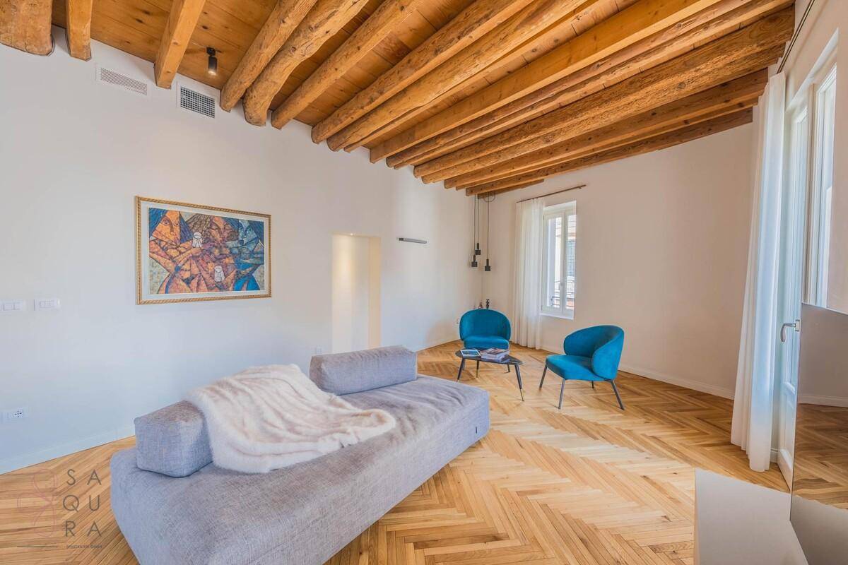 Gemütliches Wohnzimmer mit Holzbalkendecke, Fischgrätparkett und bequemer Couch.