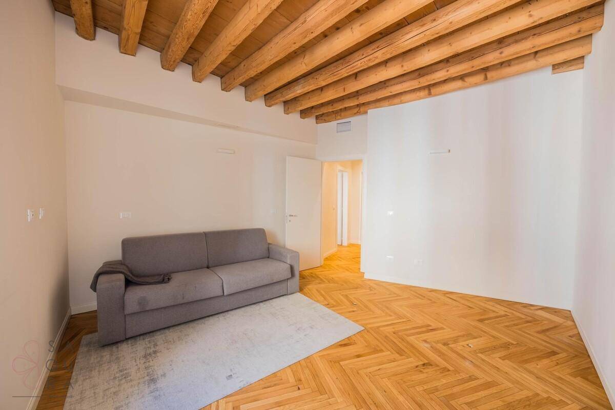 Geräumiges Zimmer mit Holzbalkendecke, Fischgrätparkett und einem bequemen Schlafsofa.