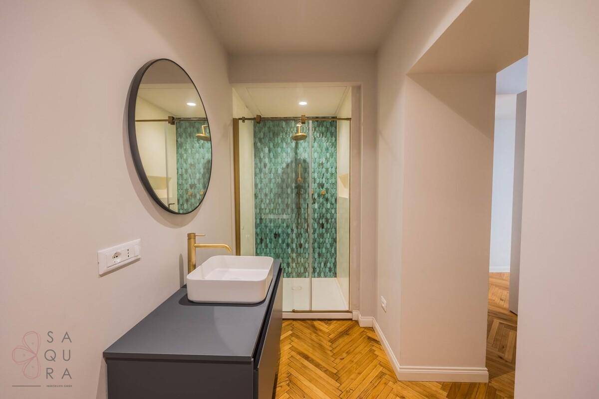 Modernes Badezimmer mit Fischgrätparkett, Aufsatzwaschbecken und Duschkabine.
