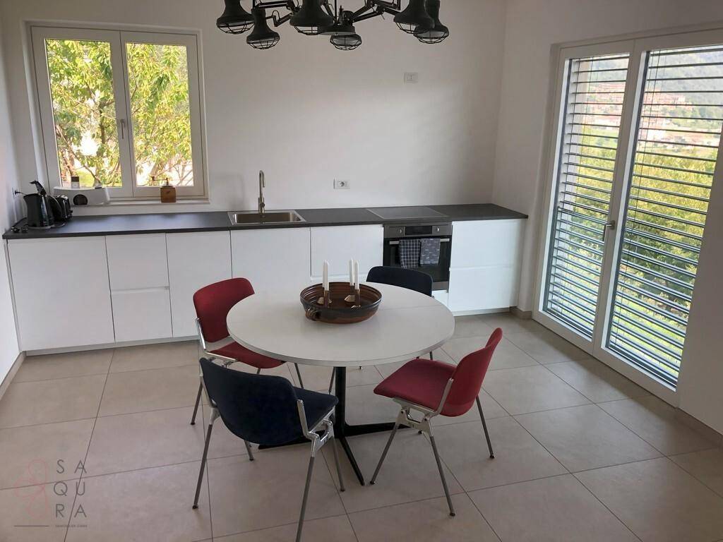 Moderne Küche mit weißen Schränken, Essbereich und Zugang zu einem Balkon.