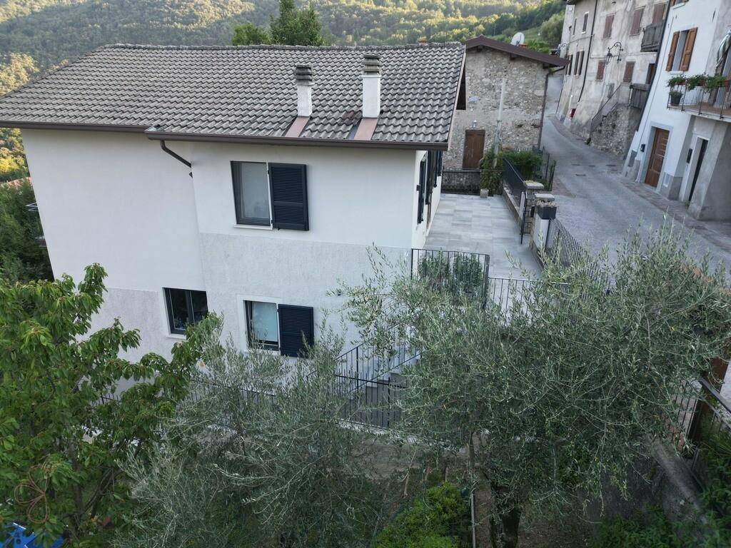 Ansicht des Hauses von oben mit Satteldach, Terrasse und Blick auf die umliegende Bebauung.