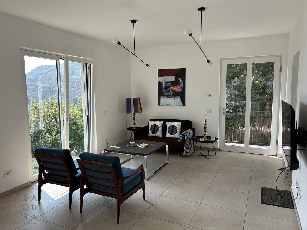 Helles Wohnzimmer mit modernen Möbeln, Fliesenboden und Zugang zu zwei Balkonen.