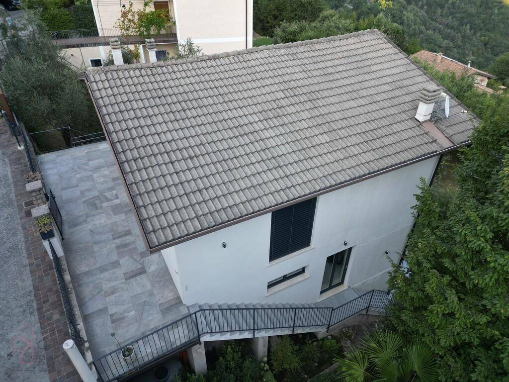 Dachansicht des Hauses mit Ziegeln und gepflasterter Terrasse, umgeben von grüner Landschaft.