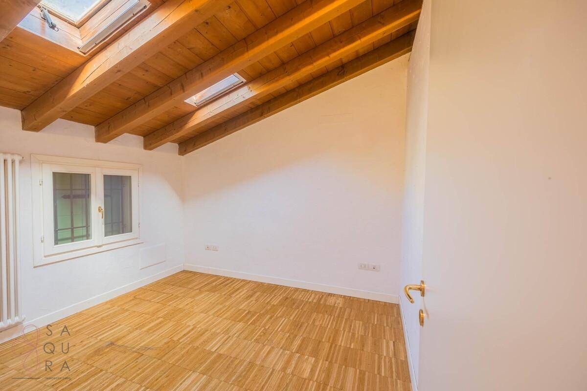 Helles Schlafzimmer mit Holzbalkendecke, Dachfenstern und Holzboden.