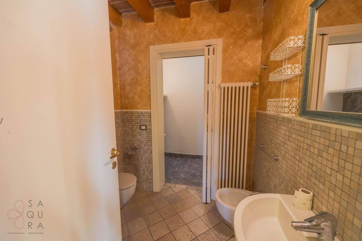 Kleines Badezimmer mit Mosaikfliesen, Bidet, Waschbecken und Toilette.