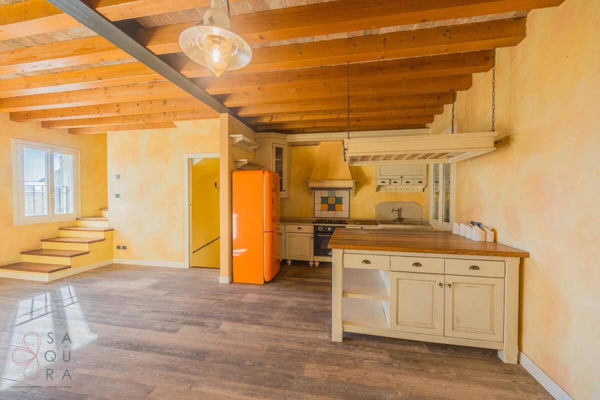 Gemütlicher Wohn-Essbereich mit Holzboden, Holzbalkendecke und traditioneller Küche.