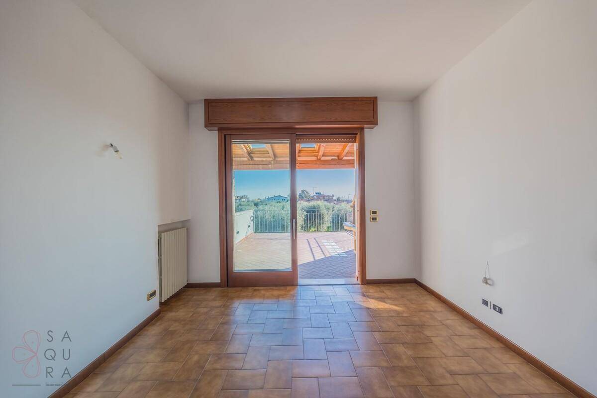 Heller Raum mit Fliesenboden und großen Glasschiebetüren, die auf eine sonnige Terrasse führen.