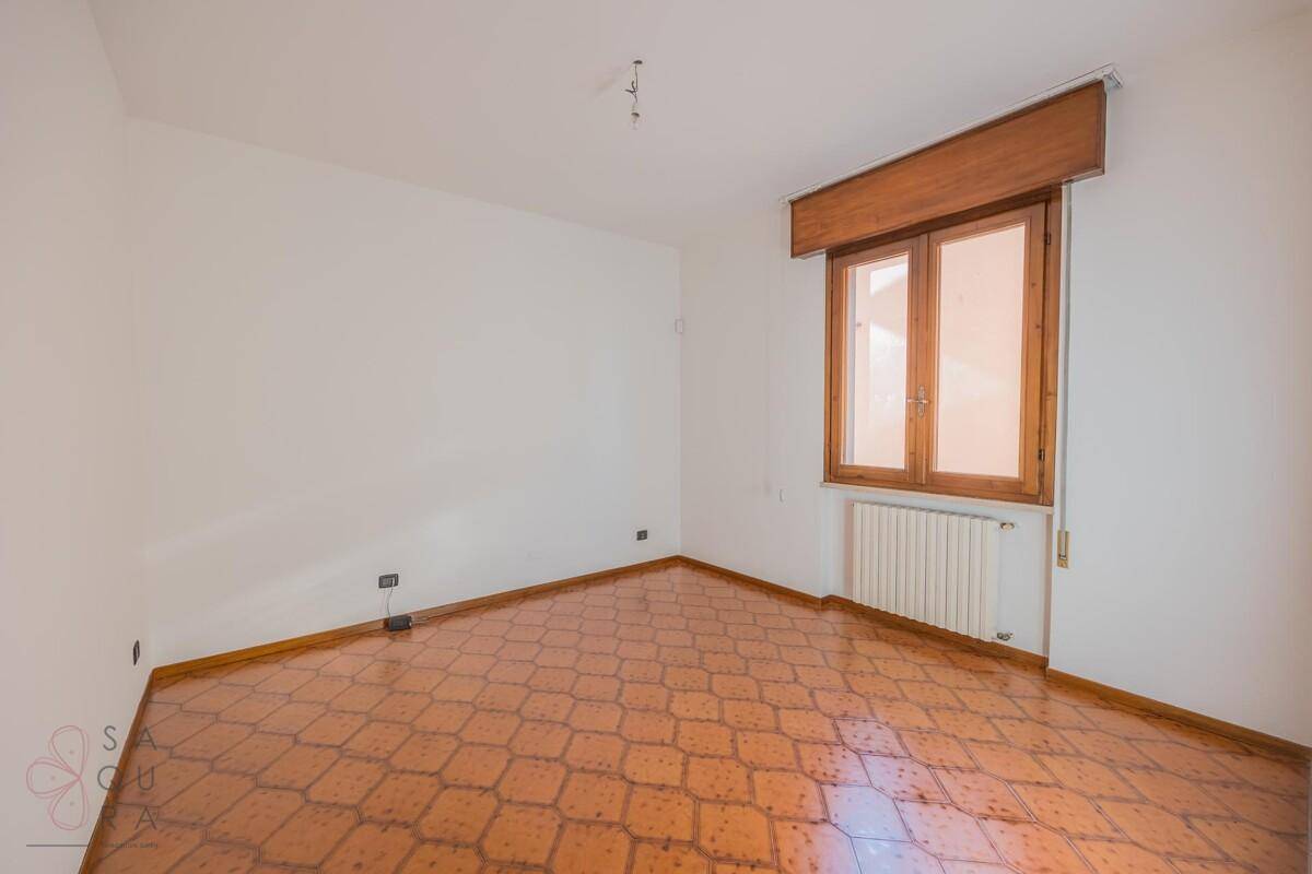 Helles Zimmer mit gemustertem Fliesenboden und einem Fenster, das viel Tageslicht hereinlässt.