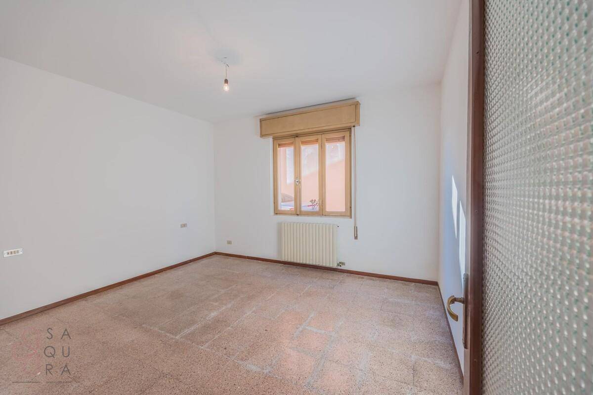 Schlichtes Zimmer mit Terrazzoboden und Fenster, das viel Tageslicht in den Raum bringt.