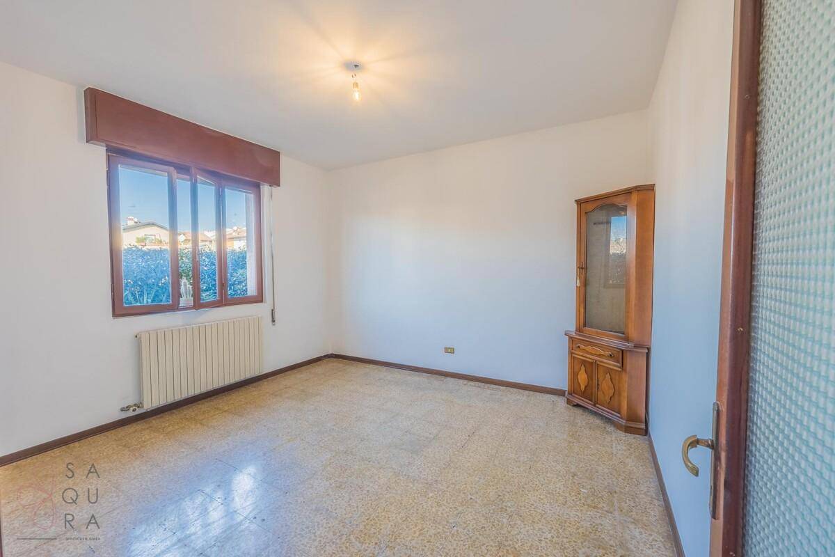 Einfaches Zimmer mit Terrazzoboden, weiß gestrichenen Wänden und einem Fenster.